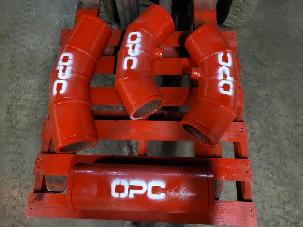 Three custom-angle Hrd67 elbows with bungs and one spool, red enamel, on a pallet at the shop