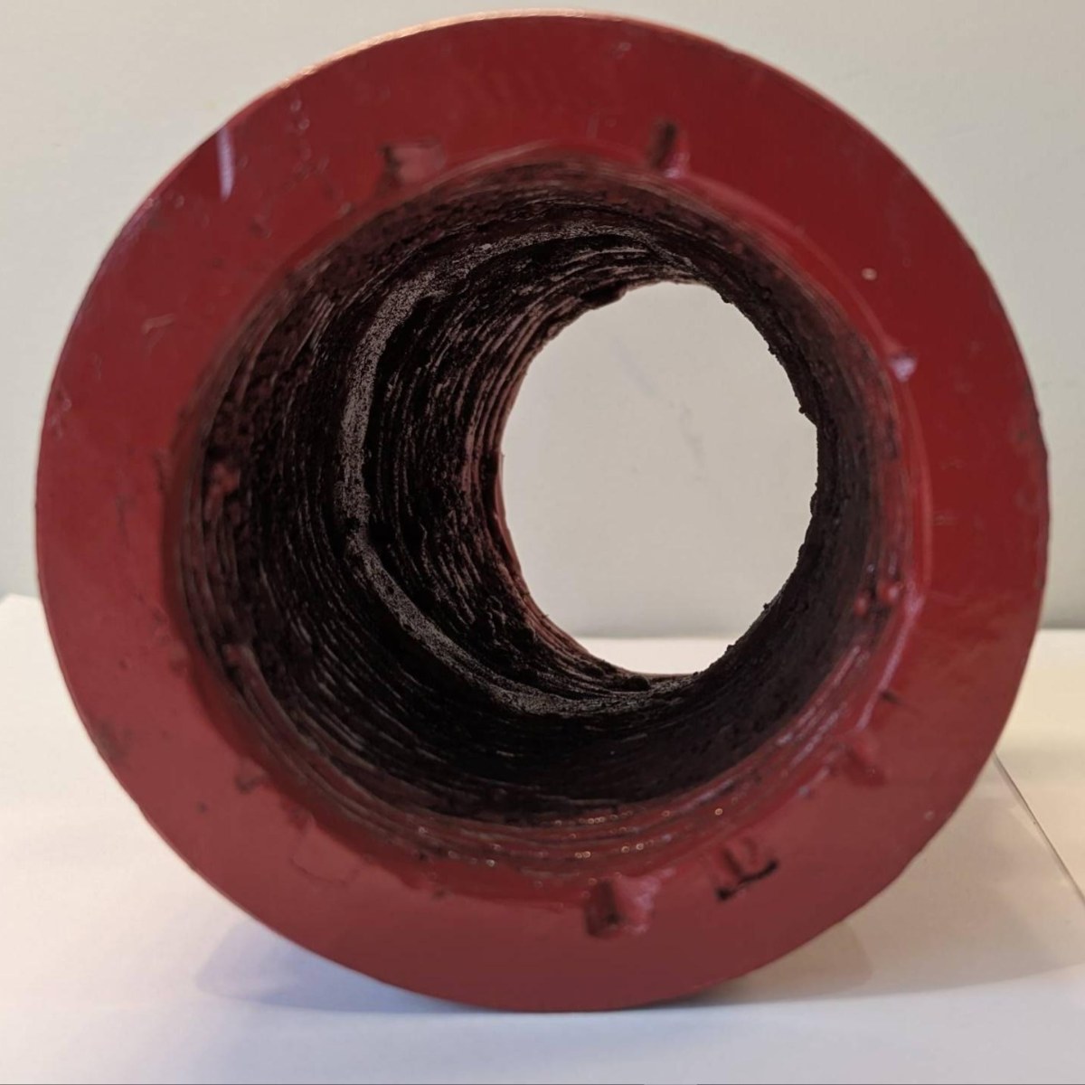 End view of a fabricated 3" 22.5&deg; Hrd67 elbow: the bare weld deposit fills the bore in circumferential rings, with the red-enamelled end face and groove around it