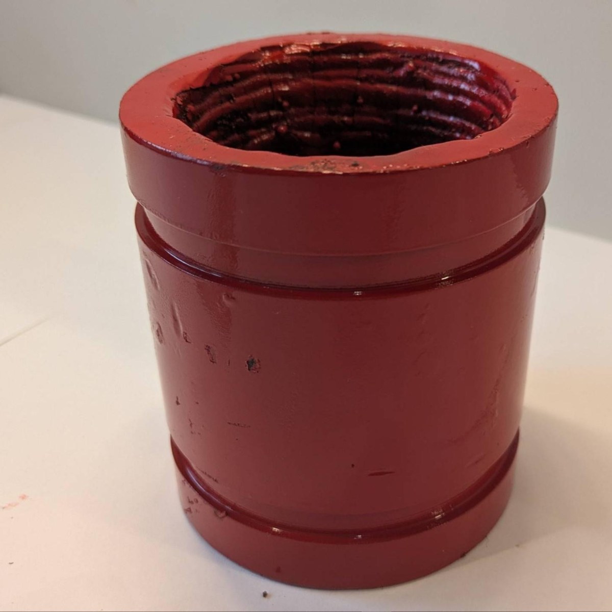 Fabricated 3" &times; 4" Hrd67 spool standing upright, red enamel, the bare weld deposit visible in the bore from above